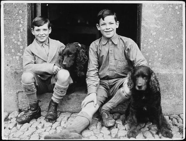 Brothers & Spaniels. Two brothers sit on a doorstep with their pet spaniels