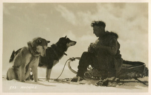 Canadian man sitting on his sled with his two huskies