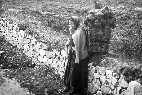Carrying turf in a creel, West of Ireland, early 1900s