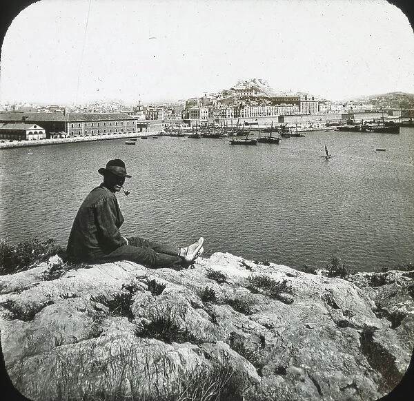 Cartagena - Black and white- man sitting on rock in foreground overlooking harbour Date
