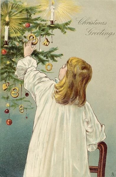 Child Dresses Tree. A girl hangs decorations on the tree - or is she helping