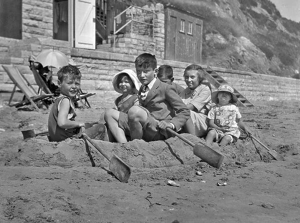 Children on Beach. Group of children in rowing boat made in the sand with spades as oars
