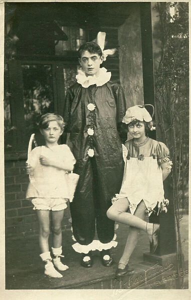 Three children in fancy dress, as cupid, a clown or pierrot