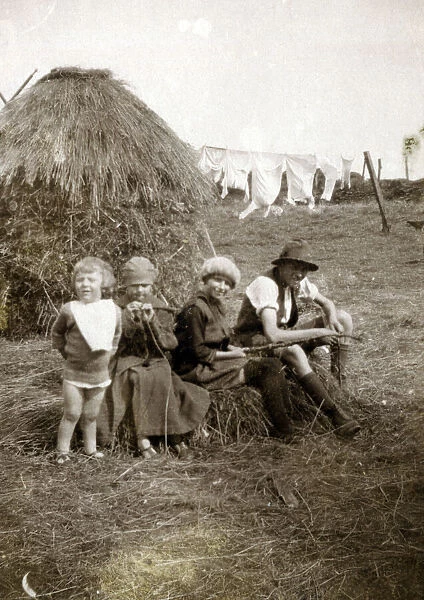 Four children sitting in a farmers field near a hayrick