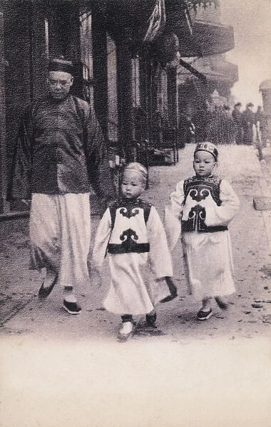 Two Chinese children in traditional attire with their Father