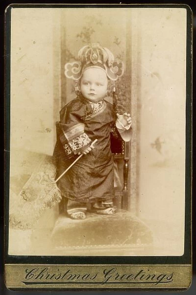 Chinese Emperor Boy. A little boy poses on a chair resplendent in a Chinese