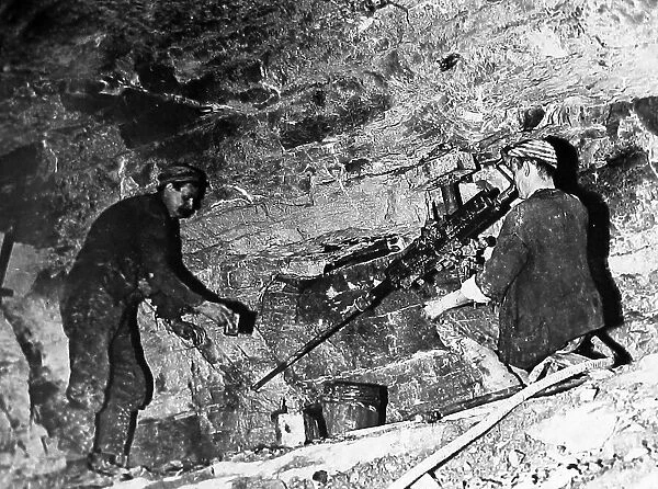 Coal miners drilling holes with a mechanised drill