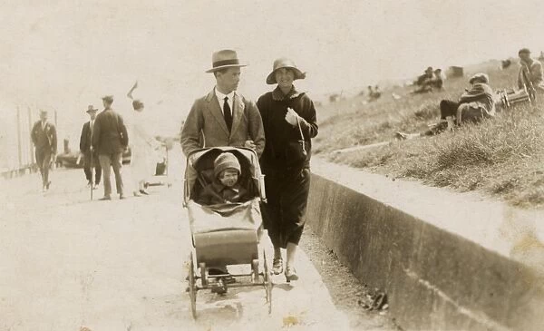 Couple strolling along the seafront with toddler in buggy