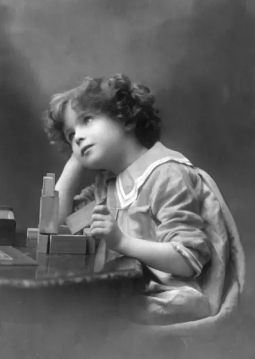 Framed Print : A curly-haired boy playing with wooden building bricks Framed Print : A curly-haired boy playing with wooden building bricks