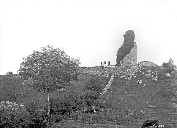 Derelict castle with people standing beside the tower stump