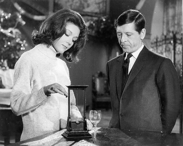 Emma Peel discussing a model guillotine with a protagonist