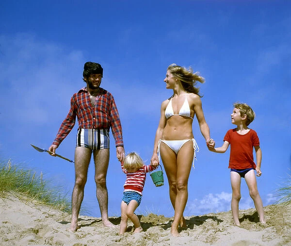 Family of four holding hands on a beach, West Country