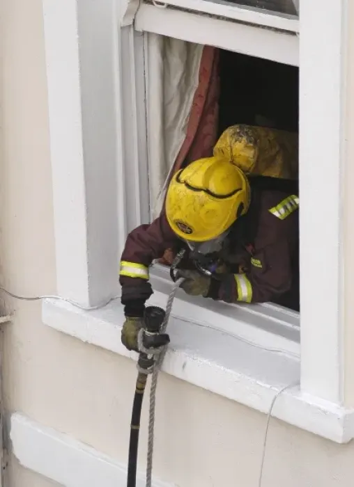Framed Print : Firefighter using a rope to pull a hose up a building Framed Print : Firefighter using a rope to pull a hose up a building