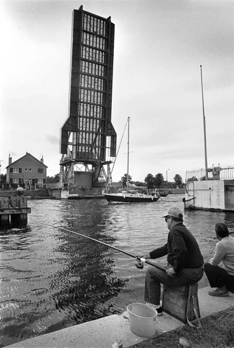 Framed Print : Fishermen on towpath as yacht passes raised Pegasus Bridge Framed Print : Fishermen on towpath as yacht passes raised Pegasus Bridge