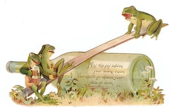 Three frogs seesawing on a cutout Christmas card
