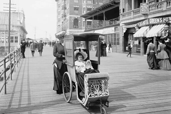 Girl with her doll in a wheeled chair on the Boardwalk, Atla