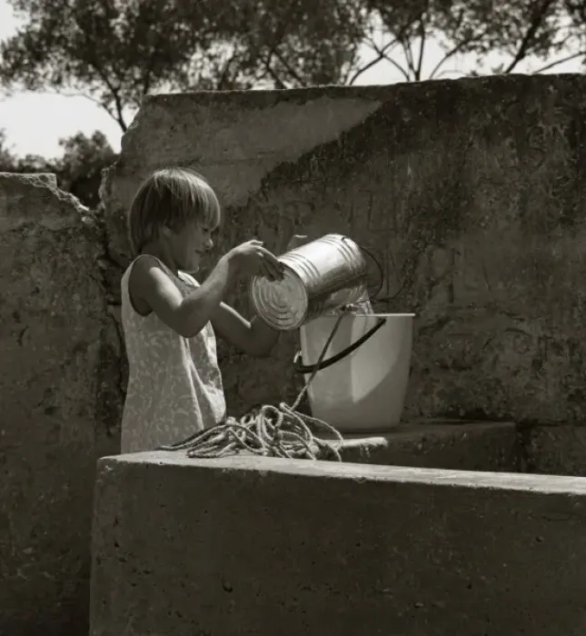 Framed Print : Girl pouring water from a tin into a bucket Framed Print : Girl pouring water from a tin into a bucket