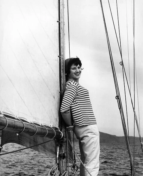 Girl in striped shirt leaning on the mast of a sailing boat