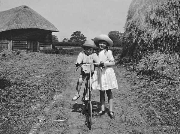 Girl and toddler riding a bicycle in a field