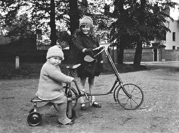 Girl and toddler riding a bicycle and a tricycle