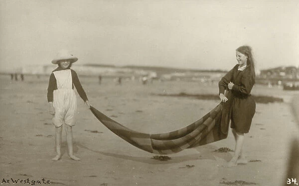 Two Girls folding up a striped blanket on the beach at Westgate-on-Sea in northeast Kent