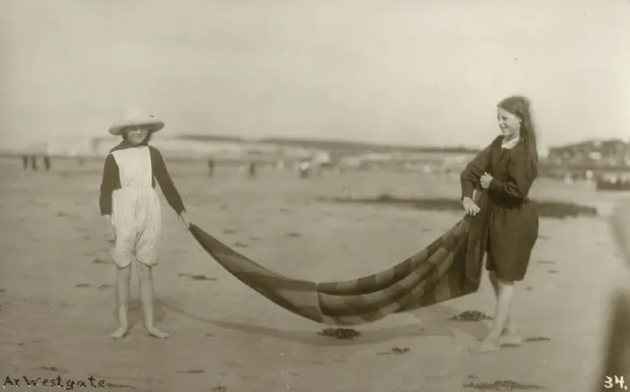 Framed Print : Two Girls folding up a striped blanket on the beach at Westgate-on-Sea in northeast Kent