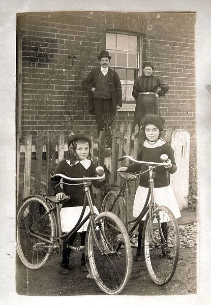 Two girls with their new bicycles and proud parents