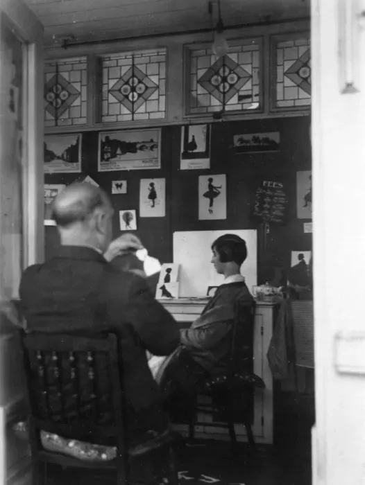 Framed Print : H. L. Oakley cutting a silhouette in his studio Framed Print : H. L. Oakley cutting a silhouette in his studio