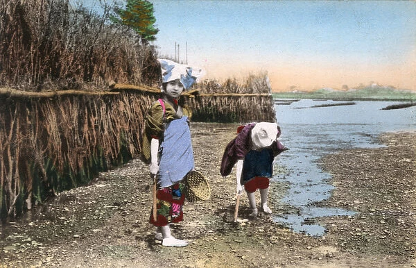 Japan, Two children digging for shellfish, low tide riverbed