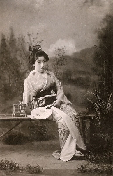 A Japanese Geisha posing in a studio garden setting