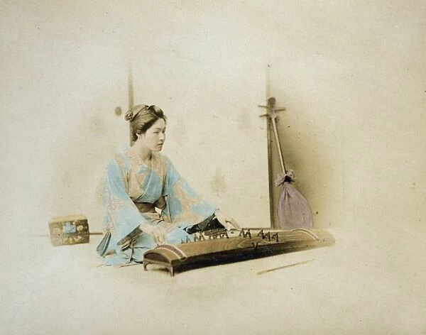 Japanese woman, full length, seated, facing right, playing a