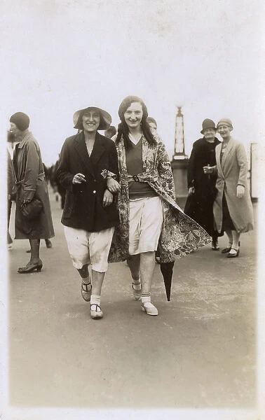 Jolly young ladies stroll confidently along the seafront