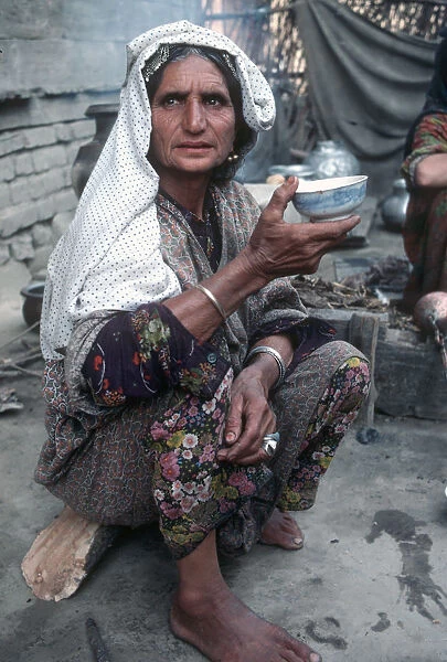 Kashmir - senior woman in traditional dress eats from bowl