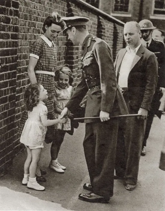 Framed Print : King George VI's visit to the bomb-shattered East End of London in September 1940: shaking hands with the little daughter, Joan Miles, of the caretaker of a school which was bombed. Date: September 1940