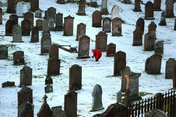 Framed Print : Lady in red coat lays bouquet on a grave, Kirkcudbright Framed Print : Lady in red coat lays bouquet on a grave, Kirkcudbright