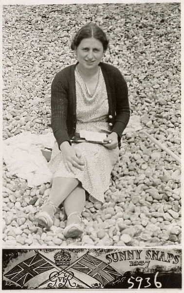 Lady on a south coast beach writing postcards to family