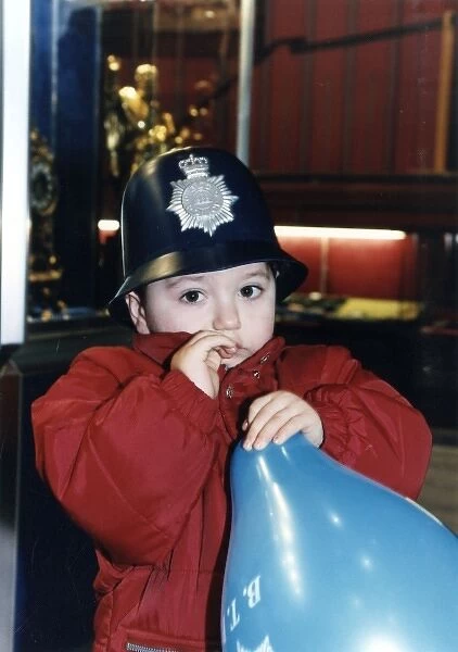 Little boy with balloon, wearing policemans helmet