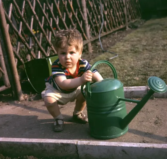 Framed Print : Little boy with green watering can in a garden Framed Print : Little boy with green watering can in a garden