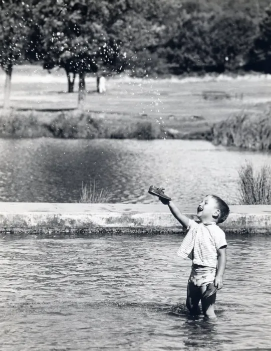 Framed Print : Little boy paddling in a pond holds up his new shoes Framed Print : Little boy paddling in a pond holds up his new shoes