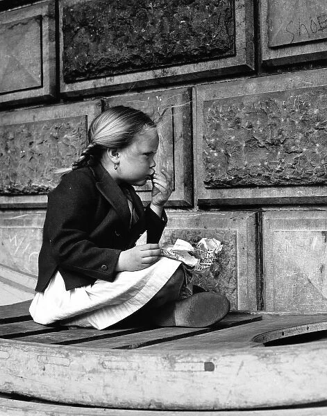 Little girl eating food out of a newspaper