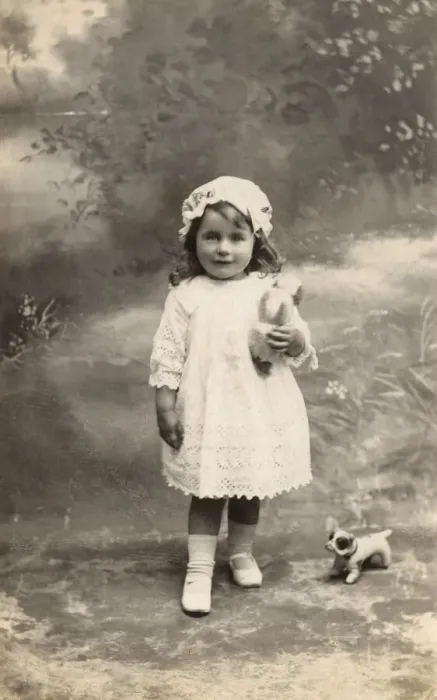 Framed Print : A little girl in lacy dress and cap poses with a toy bulldog Date: circa 1915 Framed Print : A little girl in lacy dress and cap poses with a toy bulldog Date: circa 1915