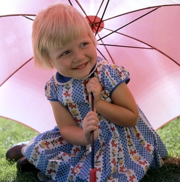 Little girl with pink parasol in garden