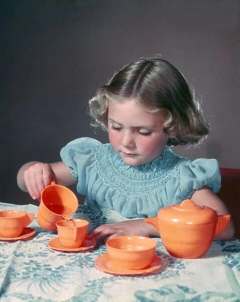 Little girl playing with toy tea set