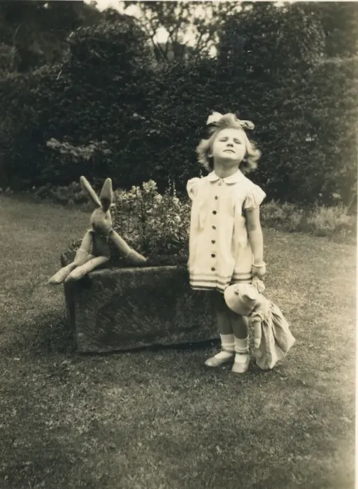 Framed Print : A little girl stands to attention and grimaces for the camera in a garden holding a doll Framed Print : A little girl stands to attention and grimaces for the camera in a garden holding a doll