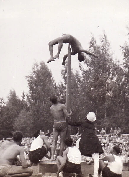 Male gymnast on pole with spectators