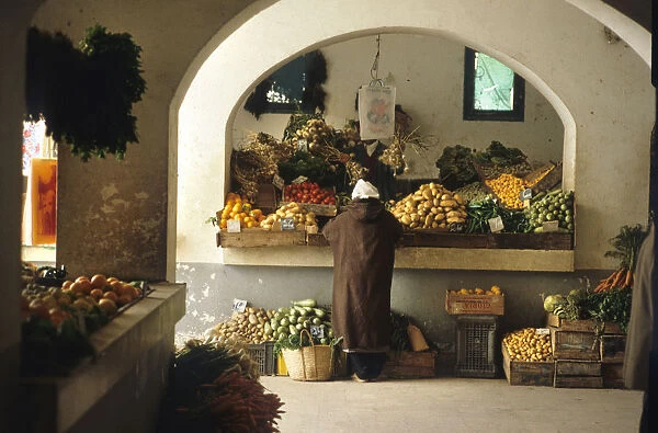 Man stands at a fruit and vegetable stall in Djerba, Tunisia