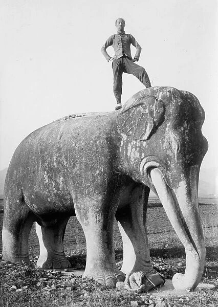 Man on top of stone elephant, Ming tombs, China, c. 1910