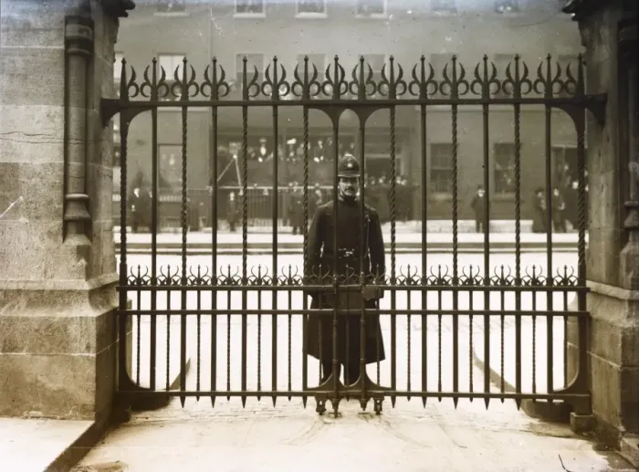 Framed Print : Met Police officer looking through iron gates Framed Print : Met Police officer looking through iron gates