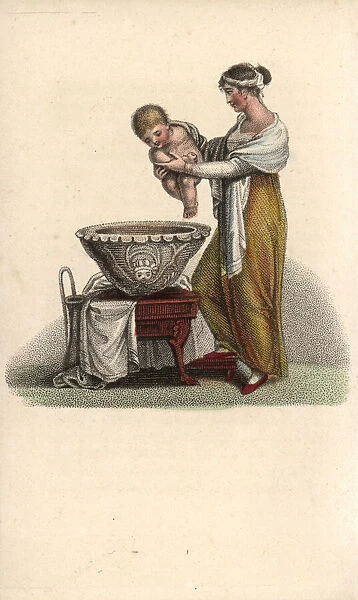 Mother putting her baby into a bath
