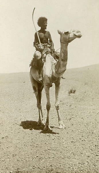 A nomad riding a camel in the desert